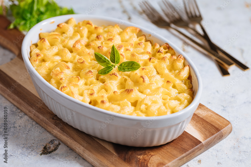 Mac and cheese with basil on top on a rustic wooden board Mac and cheese with basil on top on a rustic wooden board