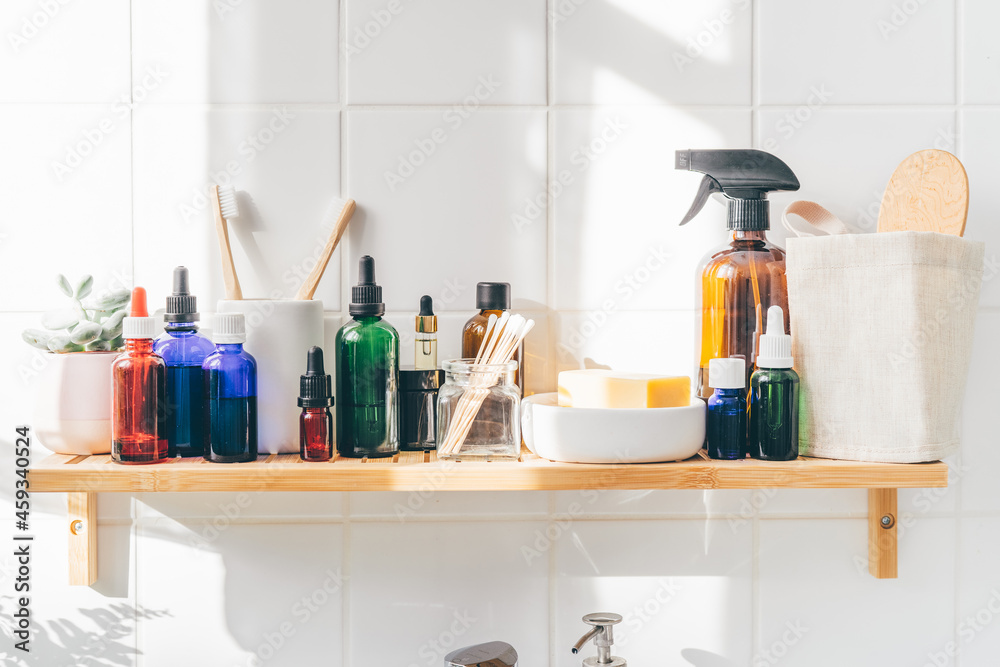 Close up of reusable cosmetic bottles on bamboo shelf against white wall. Zero waste, wellness concept Close up of reusable cosmetic bottles on bamboo shelf against white wall. Zero waste, wellness concept