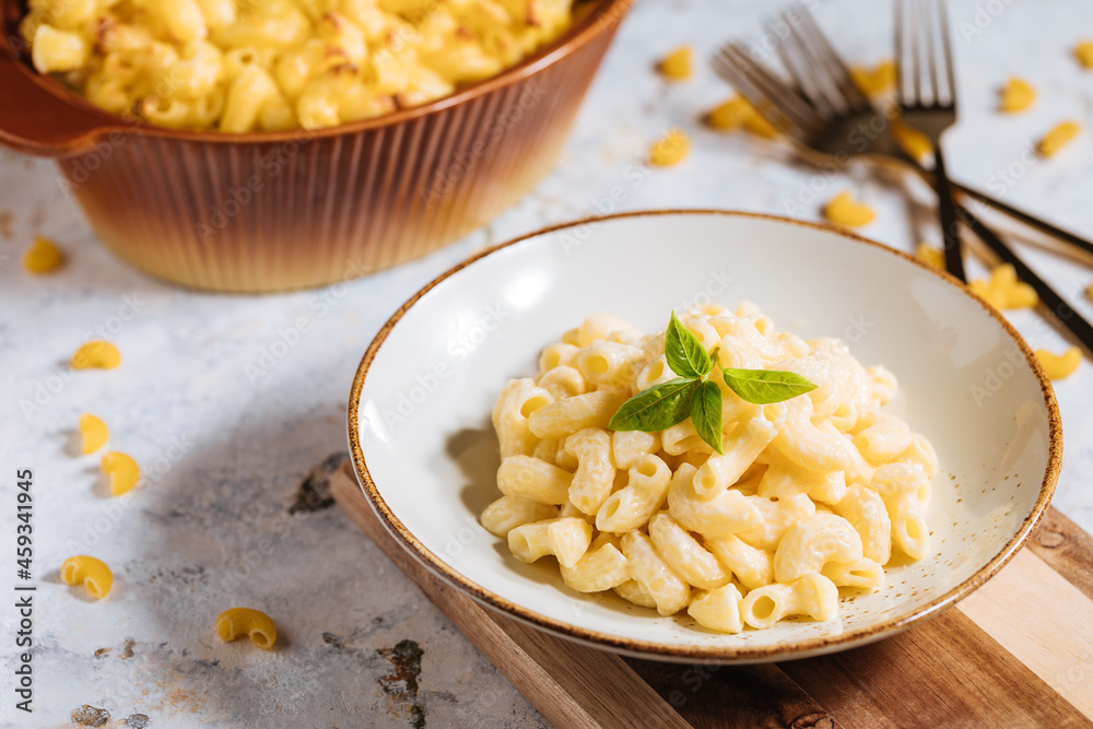 Mac and cheese with basil on top on a rustic wooden board Mac and cheese with basil on top on a rustic wooden board