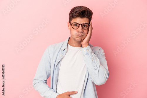 Young caucasian man isolated on pink background blows cheeks, has tired expression. Facial expression concept.