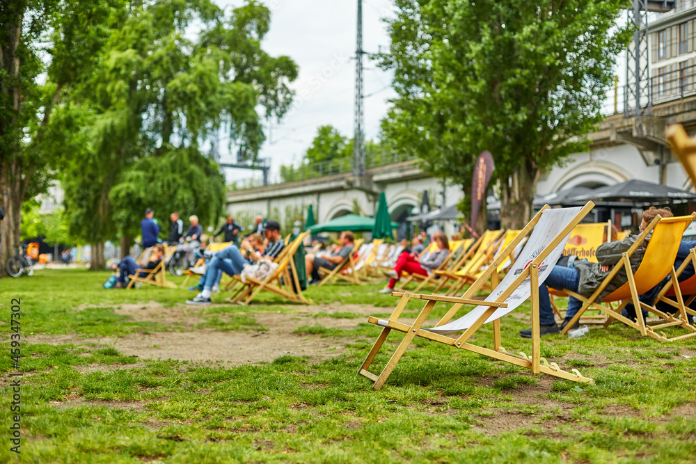 People are relaxing in small groups sitting on a green lawn in a city park in Berlin People are relaxing in small groups sitting on a green lawn in a city park in Berlin
