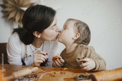 Cute little girl and mother making together christmas gingerbread cookies. Happy mom kissing adorable toddler daughter. Lovely Mommy daughter moments, happy family. Holiday preparations