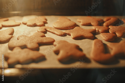 Delicious ready gingerbread cookies on paper on tray close up in oven. Christmas cookies baking in oven. Holiday preparation, xmas culinary. Biscuits recipe