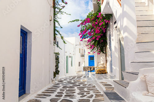 Famous old town narrow street with white houses and Bougainvillea flower. Mykonos island, Greece