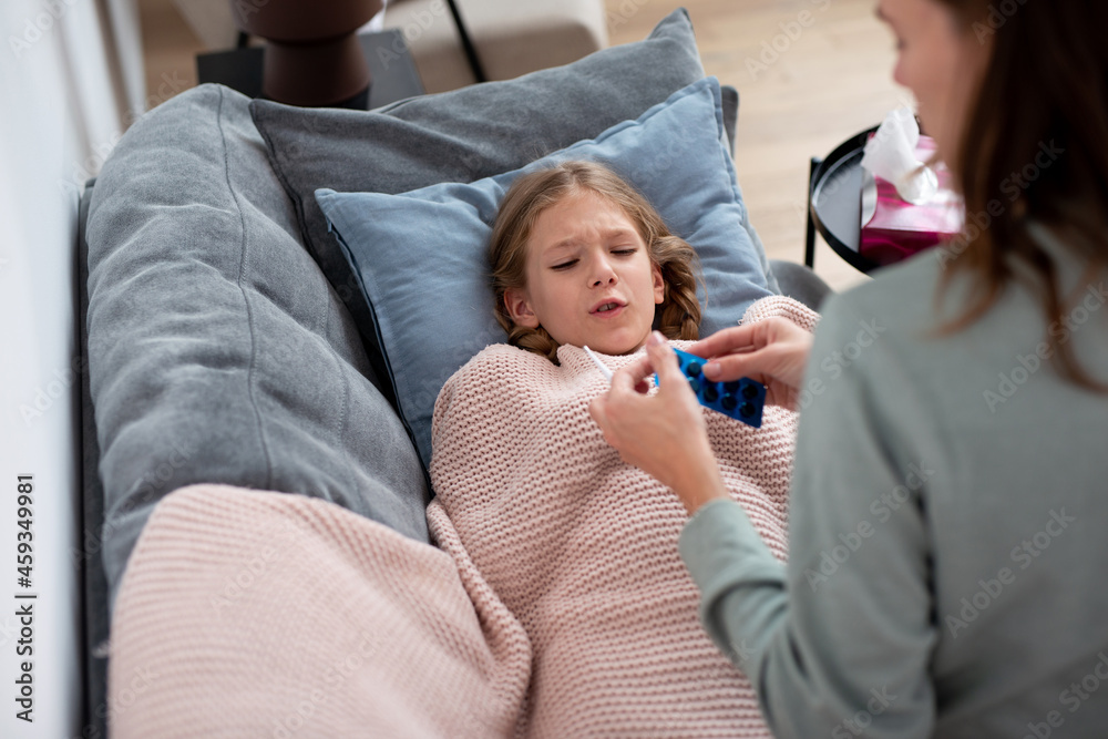 Mother gives bitter pills to daughter who has a cold Mother gives bitter pills to daughter who has a cold