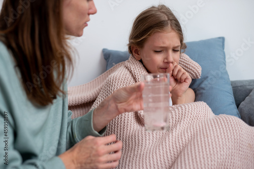 Mother gives her daughter a medicinal drink with a fizzy tablet