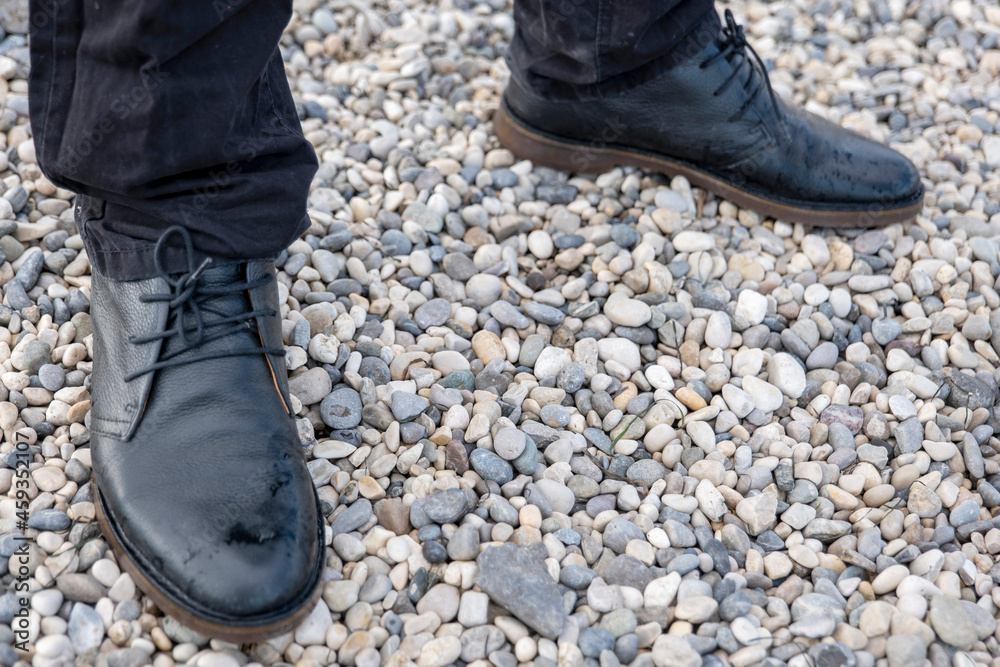 man in black boots and black pants on a rocky beach