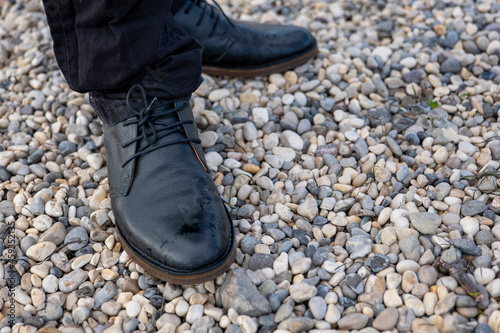 man in black boots and black pants on a rocky beach