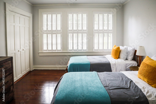 A guest bedroom with two twin beds with turquoise and gray bedspreads and yellow decorative pillows photo