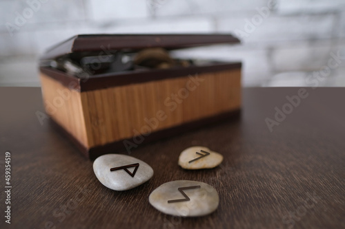 wooden brown box for storing the sacred objects of the fortuneteller, flat stones with runes for fortune telling for the future, the concept of magic and isotherics photo