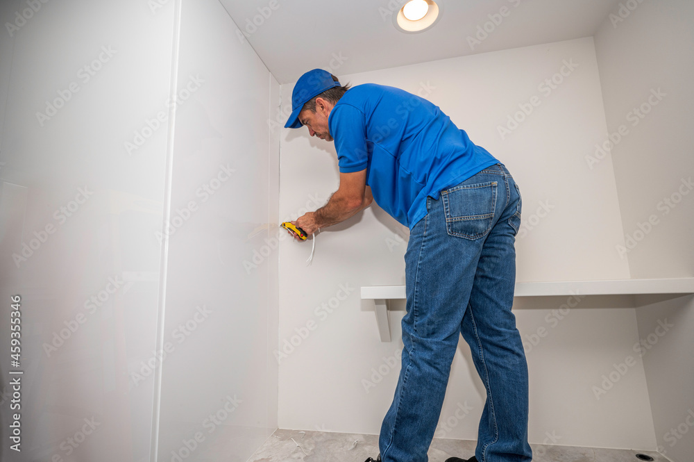 Handyman removing caulking from wall