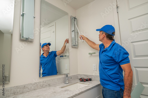 Handyman replacing a tube light in bathroom