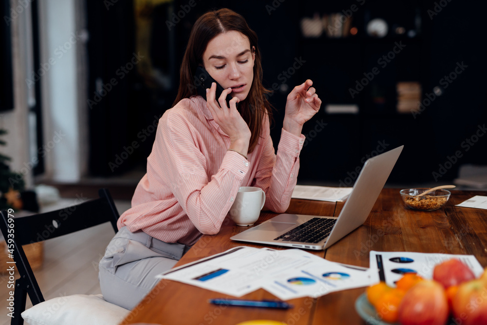 Young woman talking on smartphone while looking at her papers. Young woman talking on smartphone while looking at her papers.
