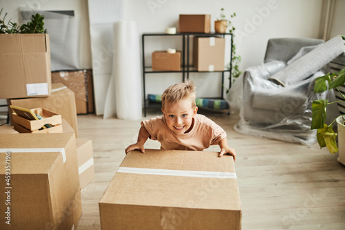 Foto Portrait of smiling little boy moving cardboard box while family relocating to n