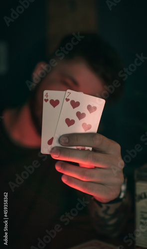 young tattooed man holding poker cards