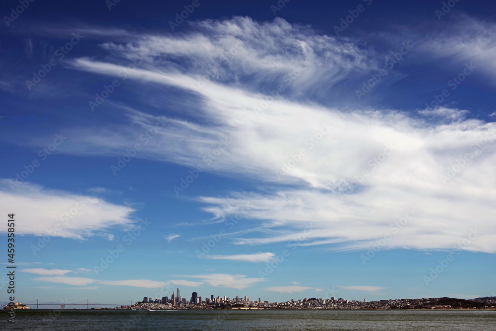 Obraz premium San Francisco under blue sky with Alcatraz and the Oakland Bay bridge seen from across the water in early August of 2021