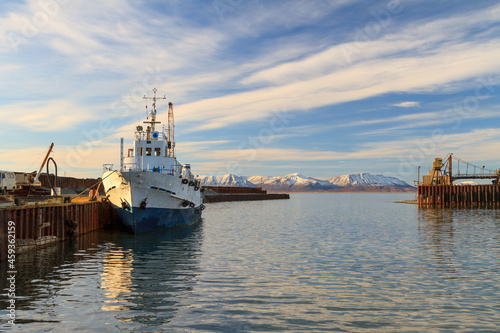 The passenger motor ship is moored near the berth in the seaport. Beautiful marine arctic landscape. View of the ship, pier, sea and mountains. Transport infrastructure. Beringovsky, Chukotka, Russia.