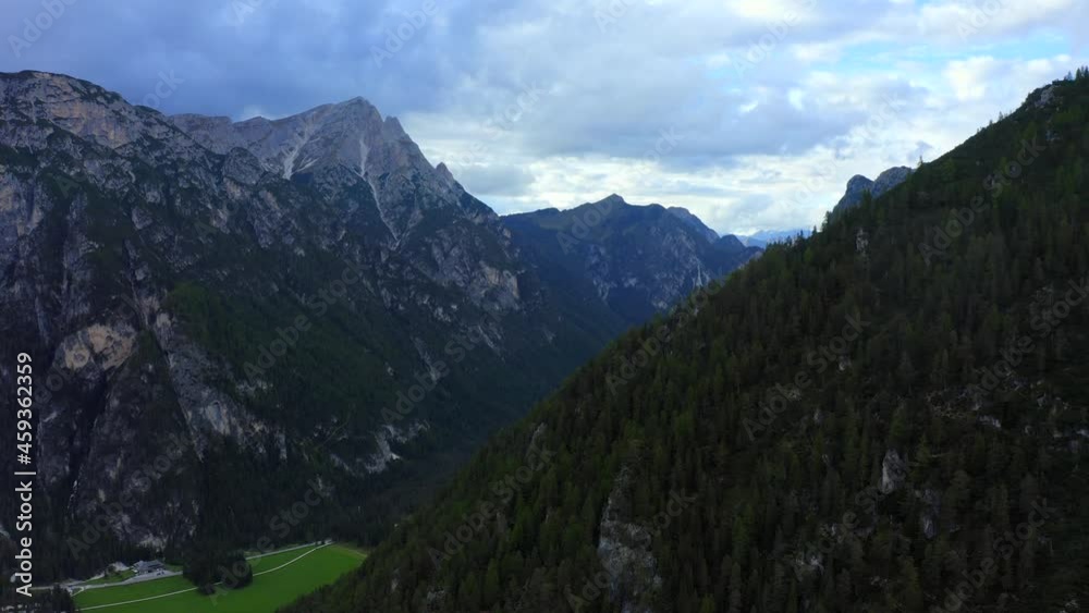 Dolomites, Three Peak National Park, South Tyrol, Italy, September 2021. Drone pushes north across dense woodland revealing a forested valley surrounded by rugged mountains. Dolomites, Three Peak National Park, South Tyrol, Italy, September 2021. Drone pushes north across dense woodland revealing a forested valley surrounded by rugged mountains.