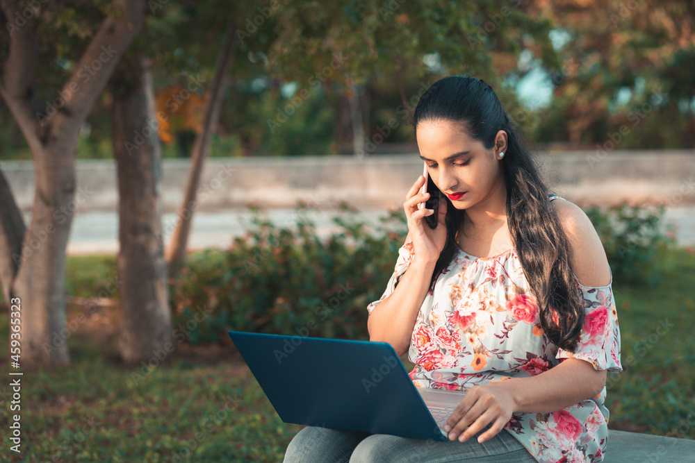 Hispanic woman talking on cell phone while sitting in park Hispanic woman talking on cell phone while sitting in park