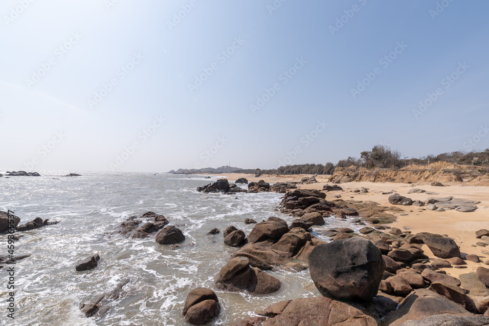 The white waves beat against the black rocks