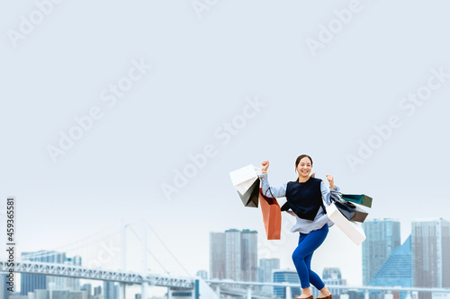 買い物袋を沢山持ってジャンプする女性（セール・爆買い） © chachamal