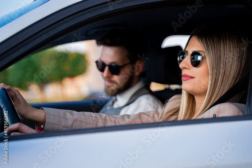 Young elegant couple in suits seating in the car, woman driving  © phoenix021