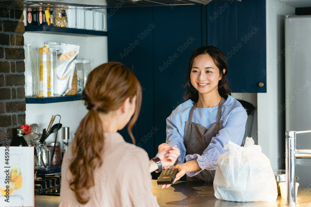 Obraz premium カフェ(飲食店)でスマートウォッチ決済をする女性