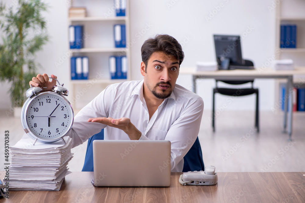 Young male employee in time management concept Young male employee in time management concept