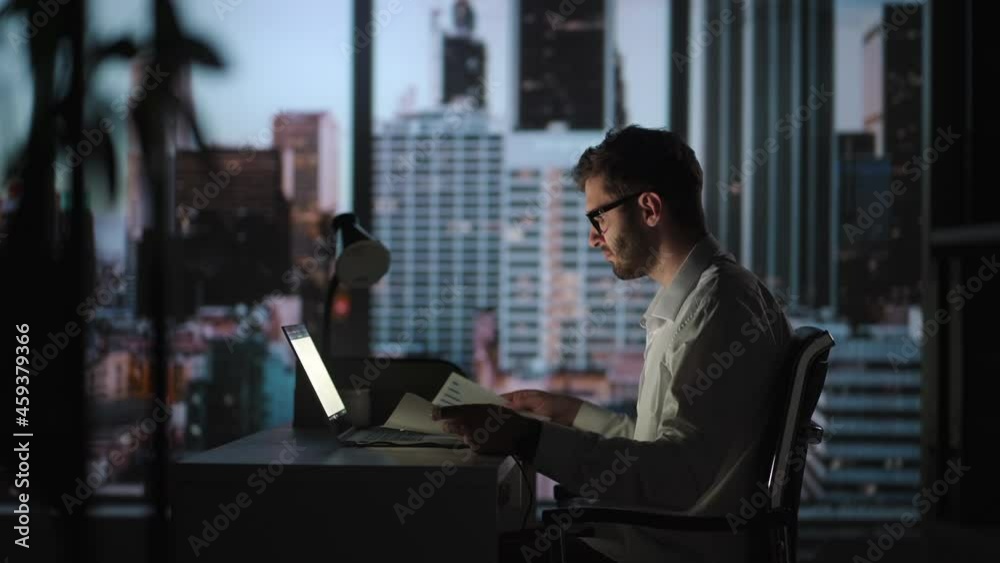 Portrait of Thoughtful Successful Businessman Working on Laptop Computer in His Big City Office at Night. Charismatic Digital Entrepreneur does Data Analysis for e-Commerce Strategy Portrait of Thoughtful Successful Businessman Working on Laptop Computer in His Big City Office at Night. Charismatic Digital Entrepreneur does Data Analysis for e-Commerce Strategy