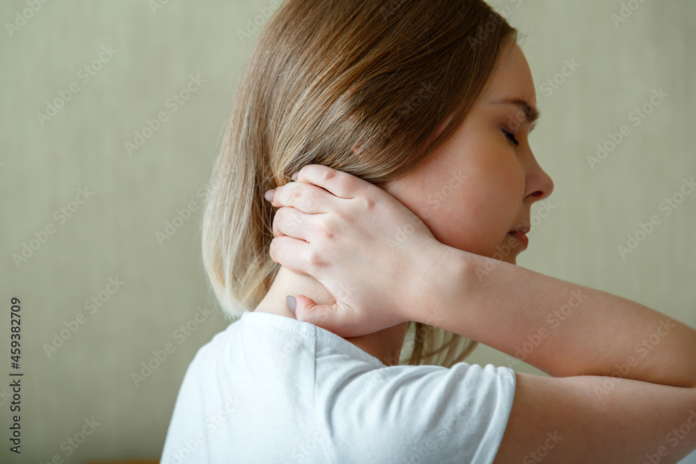 Woman holds neck with pain cervical muscle spasm by hand. Neck pain, cervical vertebrae, Disease of musculoskeletal system in young woman Woman holds neck with pain cervical muscle spasm by hand. Neck pain, cervical vertebrae, Disease of musculoskeletal system in young woman
