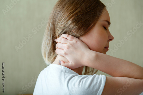 Woman holds neck with pain cervical muscle spasm by hand. Neck pain, cervical vertebrae, Disease of musculoskeletal system in young woman photo
