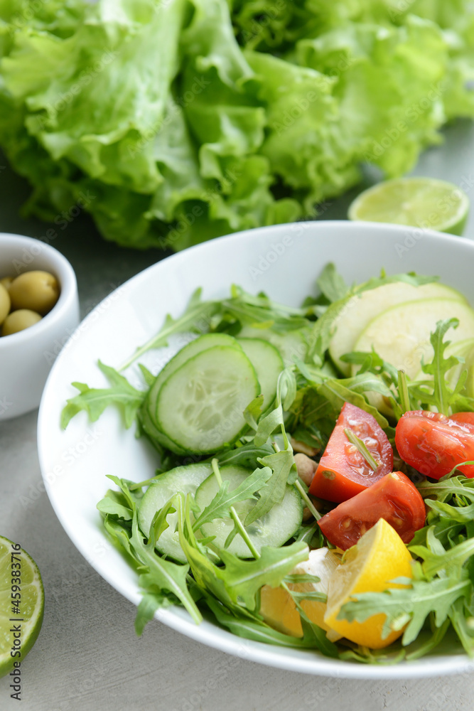 Plate with fresh salad on light background