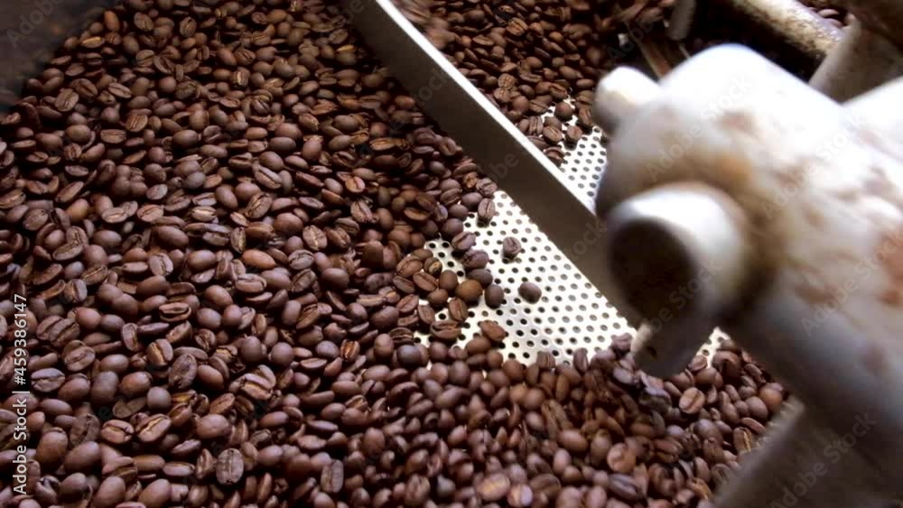 Closeup of golden brown roasted coffee beans being cooked in a commercial coffee roasting machine at local cafe Closeup of golden brown roasted coffee beans being cooked in a commercial coffee roasting machine at local cafe
