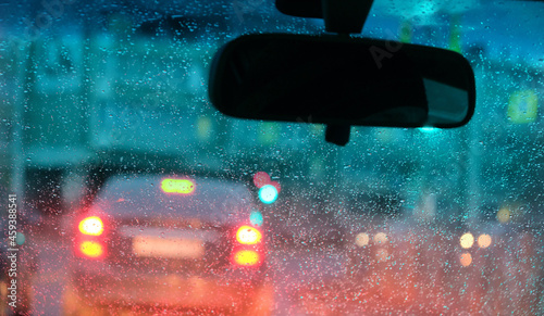 Fototapeta Naklejka Na Ścianę i Meble -  Motion blurred night city lights illuminated streets through  fogged up in small drops  car windshield