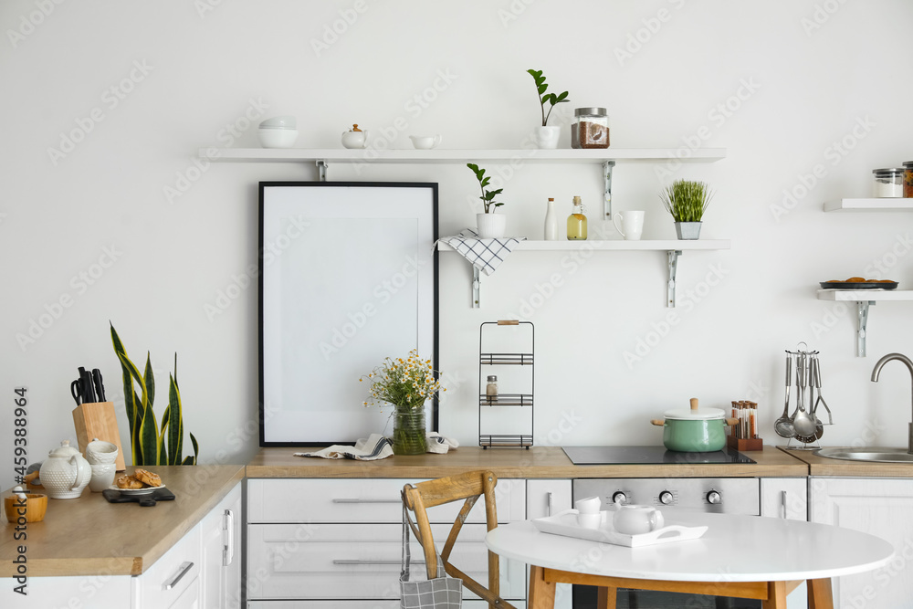 Stylish decor in light kitchen interior with blank poster frame