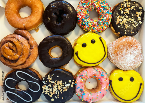 Fotografía 12 assorted colored donuts in a box, top view