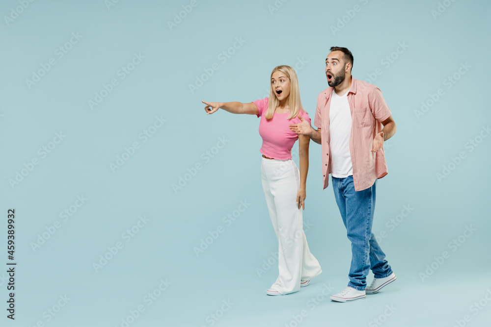 Full body young astonished couple two friends family surprised man woman 20s in casual clothes point finger aside on workspace together isolated on pastel plain light blue background studio portrait Full body young astonished couple two friends family surprised man woman 20s in casual clothes point finger aside on workspace together isolated on pastel plain light blue background studio portrait