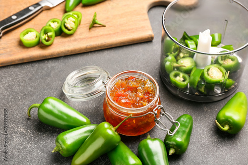 Jar with delicious jalapeno pepper jam on dark table photo