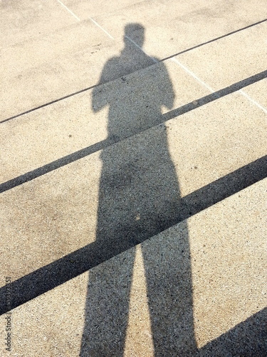 Elongated shadow of a person standing on concrete stairs