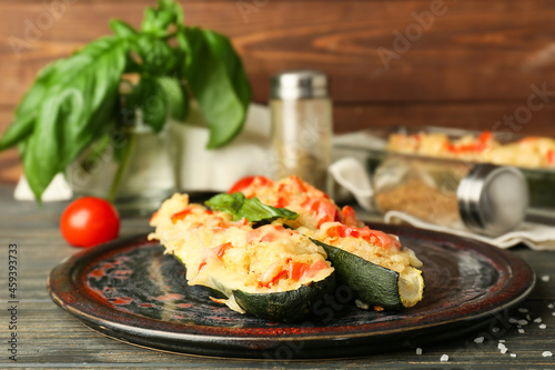 Plate with quinoa stuffed zucchini boats on wooden background