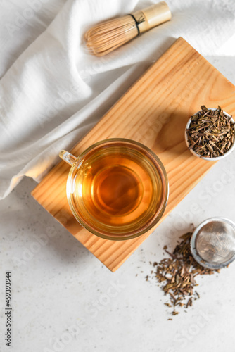 Composition with cup of tasty hojicha green tea on light background