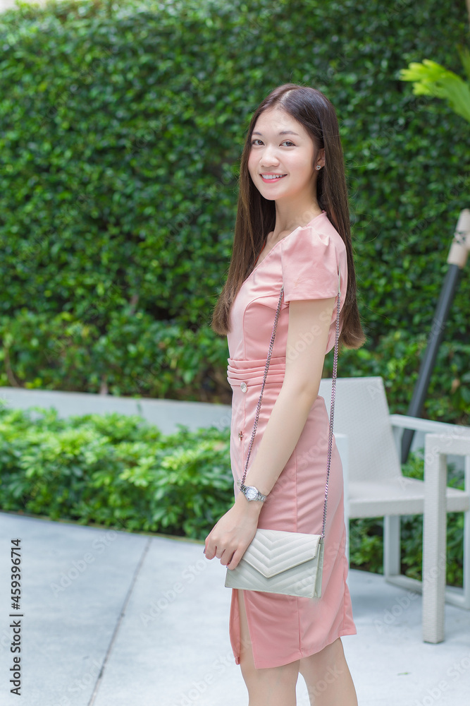 Asian professional business female with long hair is smiling in the garden while looking at the tablet in her hand, work from anywhere concept. Asian professional business female with long hair is smiling in the garden while looking at the tablet in her hand, work from anywhere concept.