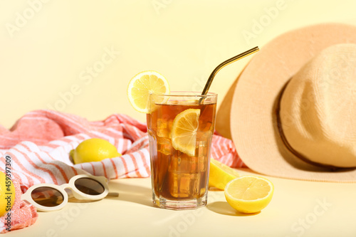 Wall Mural Glass of refreshing Long Island iced tea with lemon, sunglasses and towel on col