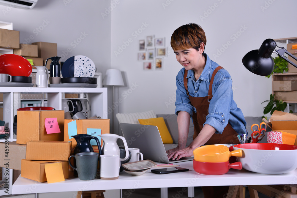 Mature Asian woman entrepreneur, Business owner working on laptop computer checking address and delivery detail before shipping product. Online selling business work at home concept Mature Asian woman entrepreneur, Business owner working on laptop computer checking address and delivery detail before shipping product. Online selling business work at home concept