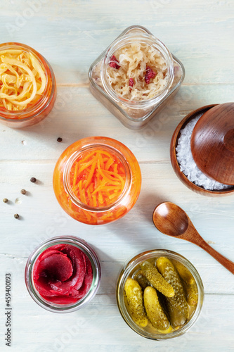 Fermented food. Canned vegetables. Pickled carrot, beet, sour cabbage and other organic preserves in glass jars, overhead flat lay shot on a rustic wooden background
