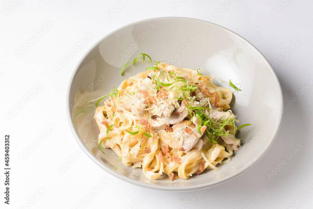 Italian tortellini pasta with cheese, sauce, and microgreens served in a white bowl. Italian cuisine concept