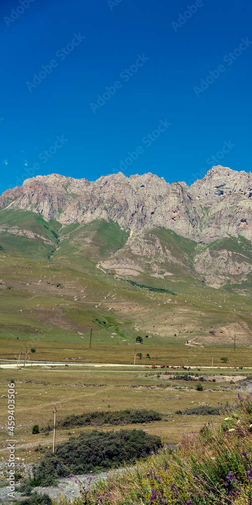 Mountains of North Ossetia, beautiful summer landscapes with blue sky and clouds. Vertical format. Mountains of North Ossetia, beautiful summer landscapes with blue sky and clouds. Vertical format.