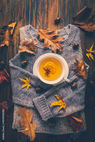 Warm swater with hot lemon tea with fall foliage on wooden background photo