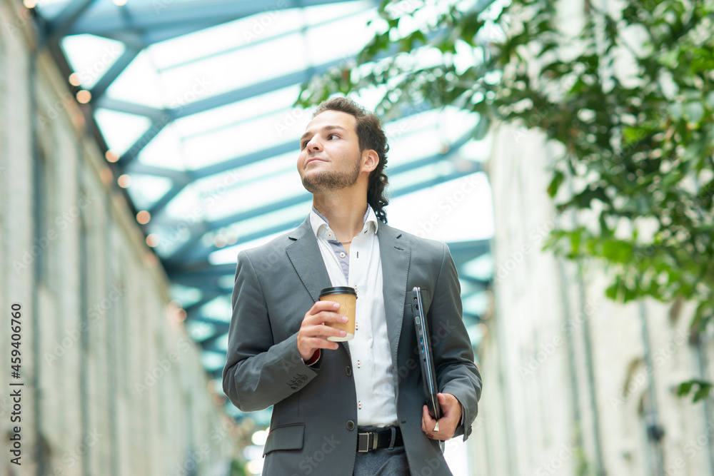 A young successful businessman is walking down the street. Man in a casual wear. Business, freelance and remote work. A young successful businessman is walking down the street. Man in a casual wear. Business, freelance and remote work.