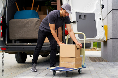 Male delivery person unloading boxes from moving van photo
